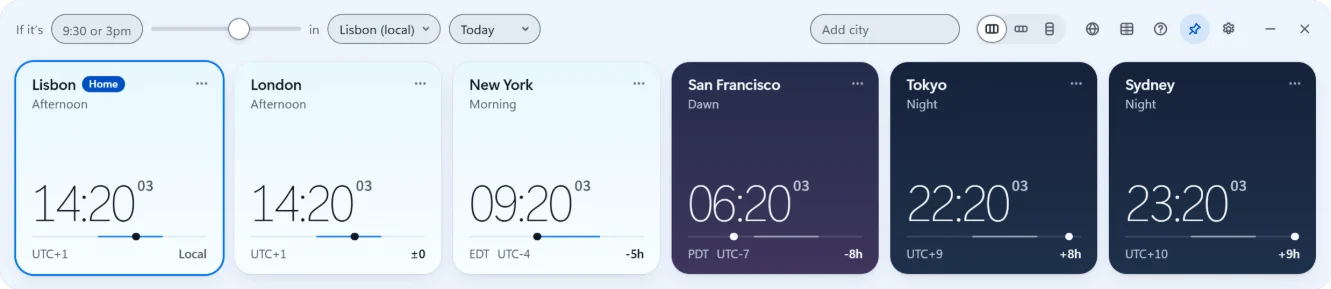 A faixa do Open World Clock no tema claro: Lisboa marcada como cidade local e Londres às 14:20, à tarde, Nova York de manhã, San Francisco ao amanhecer, Tóquio e Sydney em cartões azul-marinho, de noite.